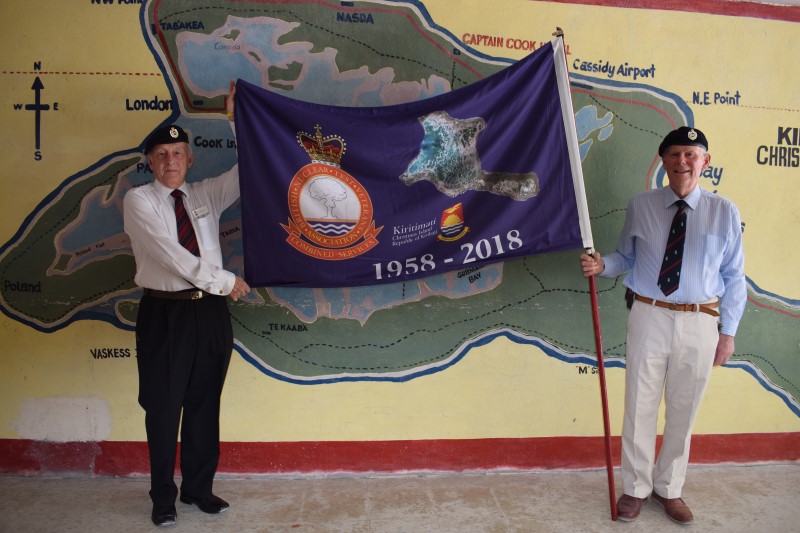 Ron Watson and Robert McCann proudly hold their standard in front of a mural of Kiritimati