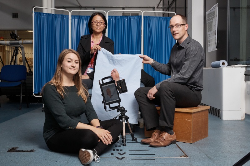 PhD researcher Katie Chatwin, left; Dr Moi Hoon Yap, Senior Lecturer in Computer Science, centre; and Professor Neil Reeves, Professor of Musculoskeletal Biomechanics, right, demonstrating the innovative FootSnap app that helps GPs take consistent photos of diabetics' feet