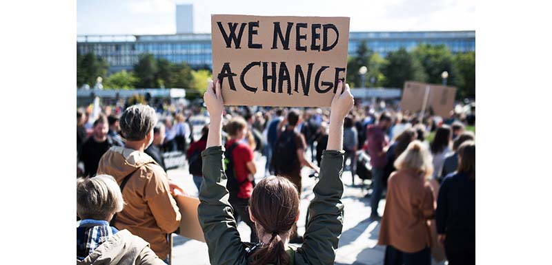 Someone holding up a banner saying 'we need change'