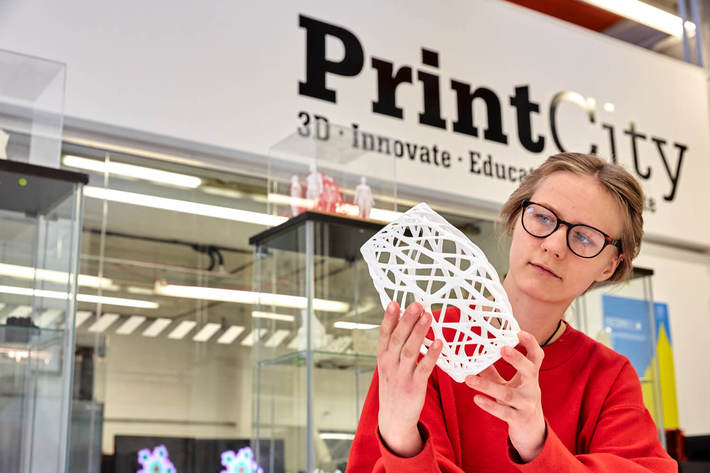 Image of a 3D printed object held by a person, in the PrintCity lab