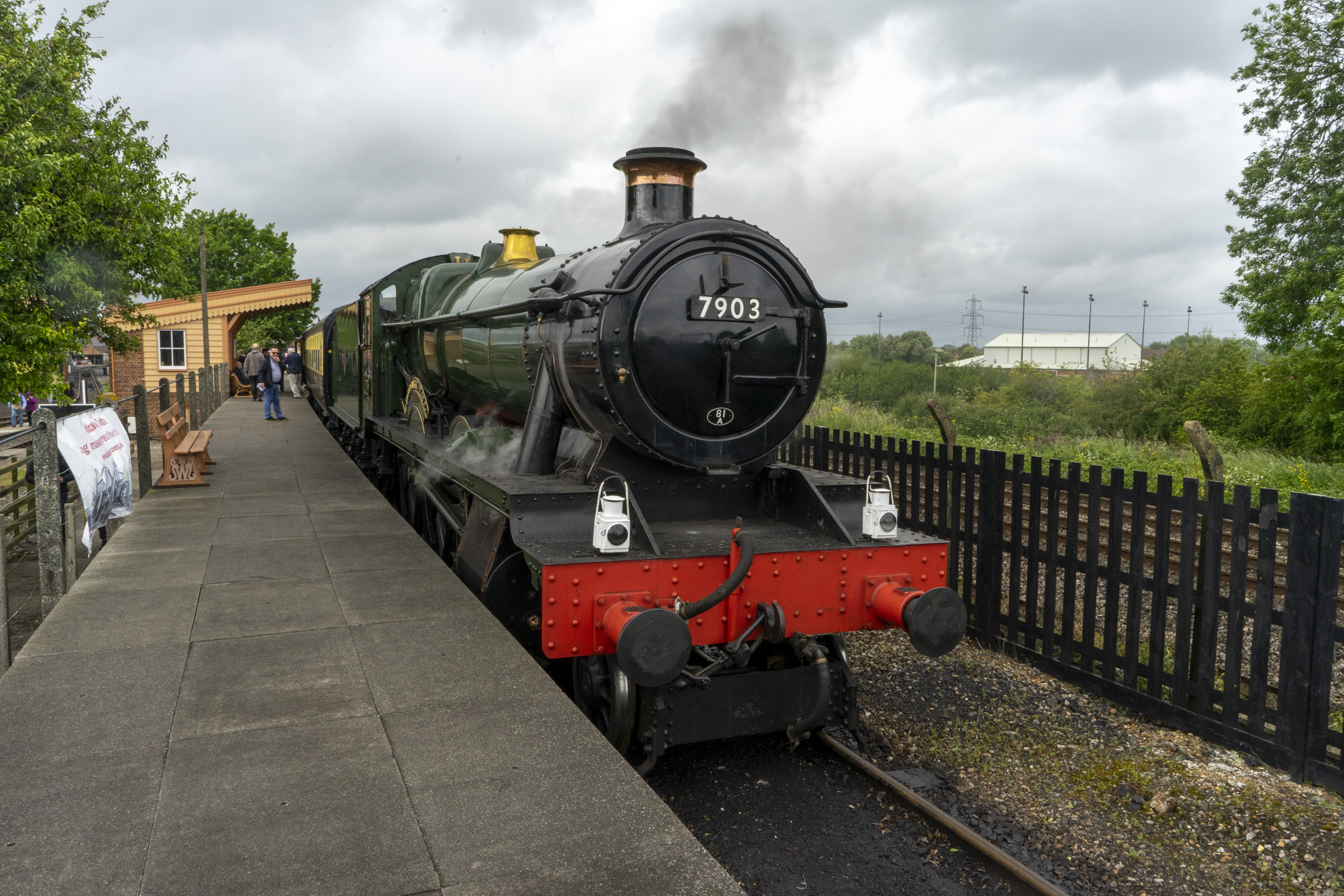 A traditional steam train pulling into a railway platform.