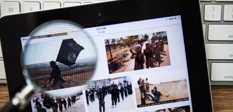 Magnifying glass looking at jihadist content on a tablet computer